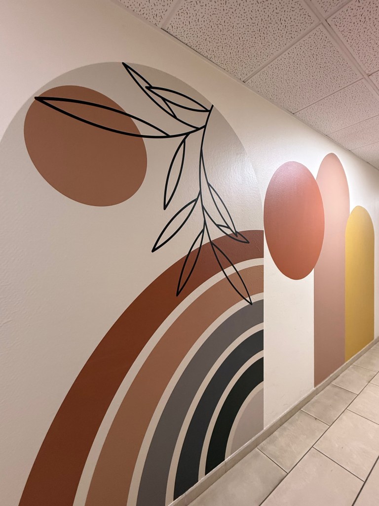 Mur décoratif avec des formes géométriques colorées et des éléments de feuillage, créant une ambiance moderne et artistique.